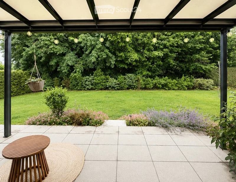 A well-maintained garden with a paved patio, wooden table, hanging basket, and lush greenery.