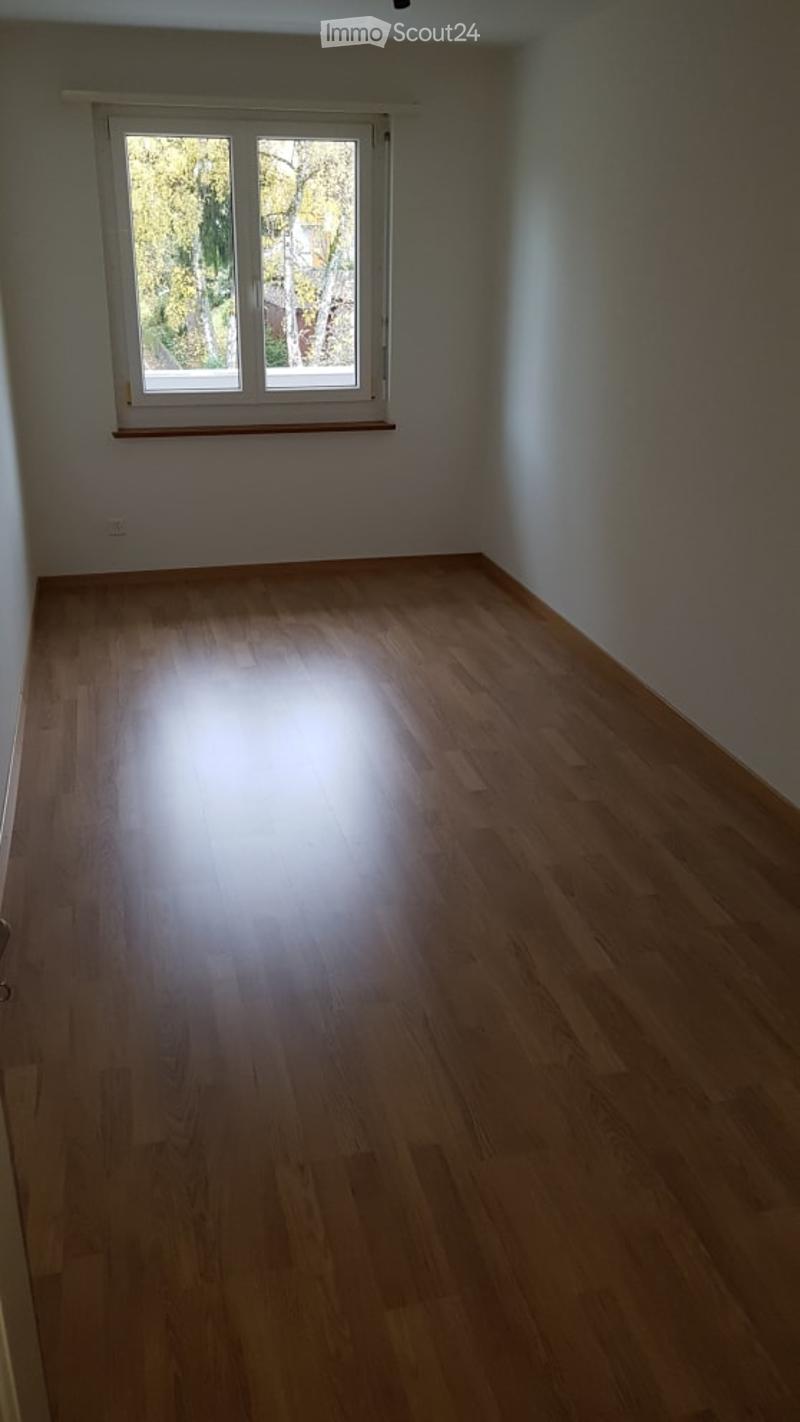 Empty room with wooden flooring and a large window letting in natural light. No furniture or equipment present.
