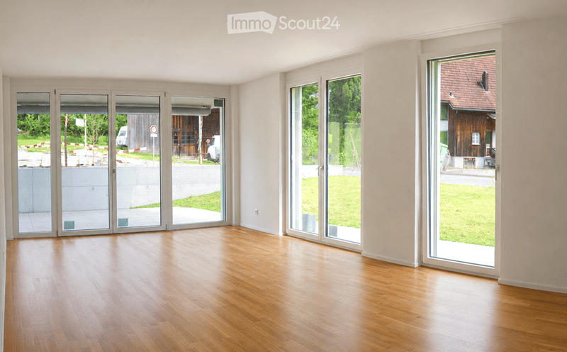 Empty room with wooden flooring and large glass doors leading to an outdoor area.