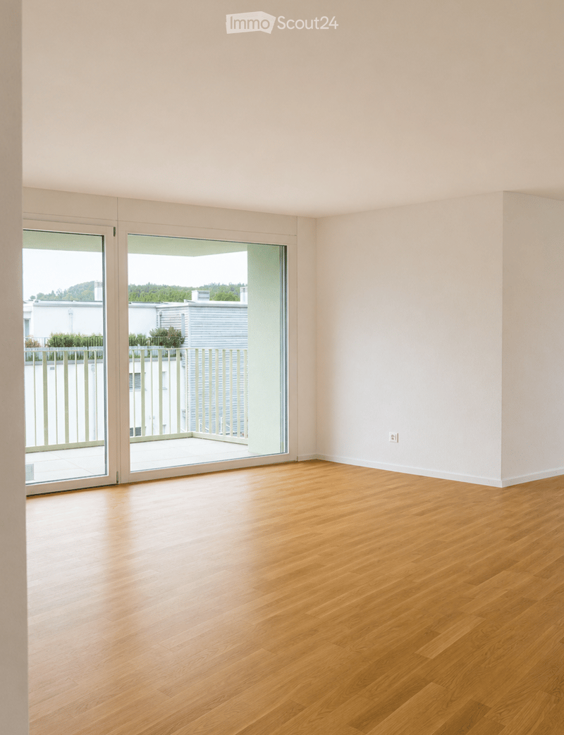 Empty room with light wooden flooring and large sliding glass doors leading to a balcony.