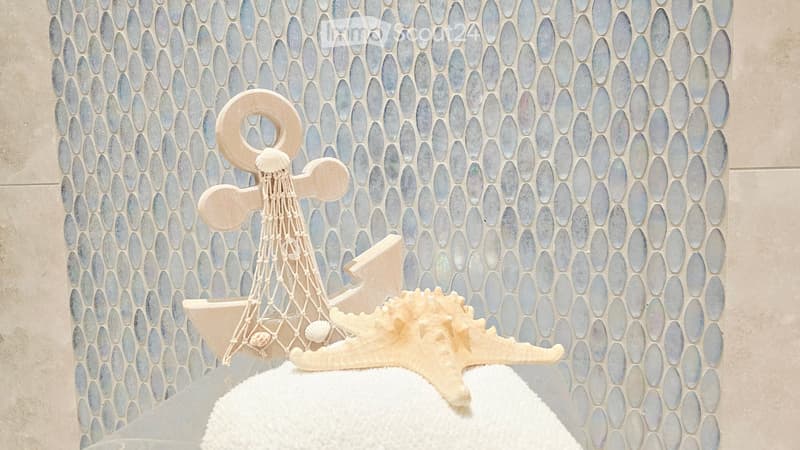 A bathroom with a decorative anchor and starfish placed on a white towel against a blue mosaic tile wall.