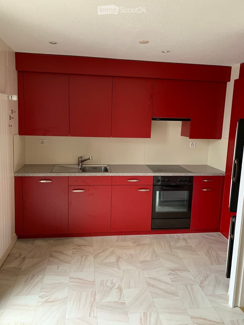 red kitchen cabinets, marble countertops, sink with faucet, black stove, black oven, white tiled floor