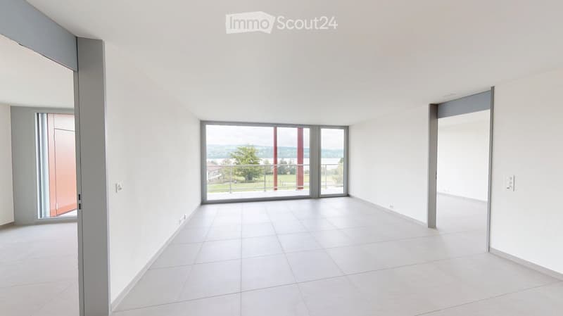 Empty room with white tiled floor, white walls, large sliding glass doors leading to a balcony with a scenic view.