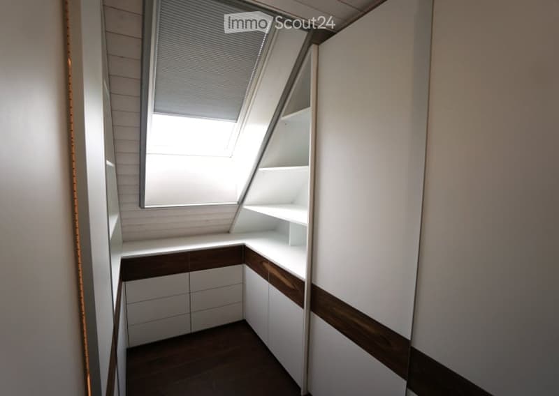 An empty room with white walls, wooden flooring, built-in cabinets, and a skylight window. No furniture or equipment is present.