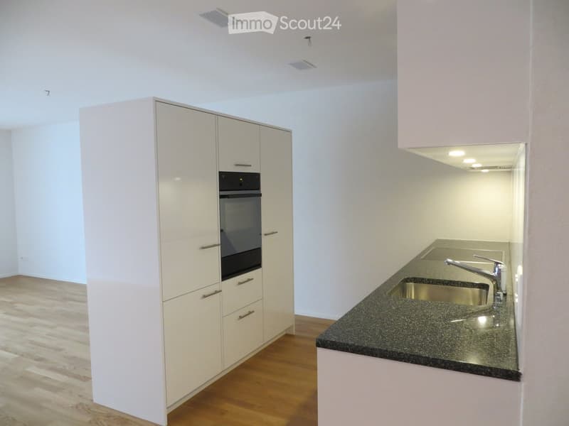 Modern kitchen with white cabinets, granite countertop, stainless steel sink, and built-in oven.
