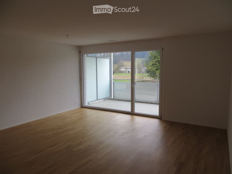 Empty room with wooden flooring and large sliding glass doors leading to a balcony.