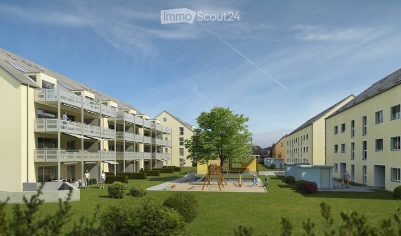 Multi-story residential building with balconies, surrounded by green lawn and playground area.