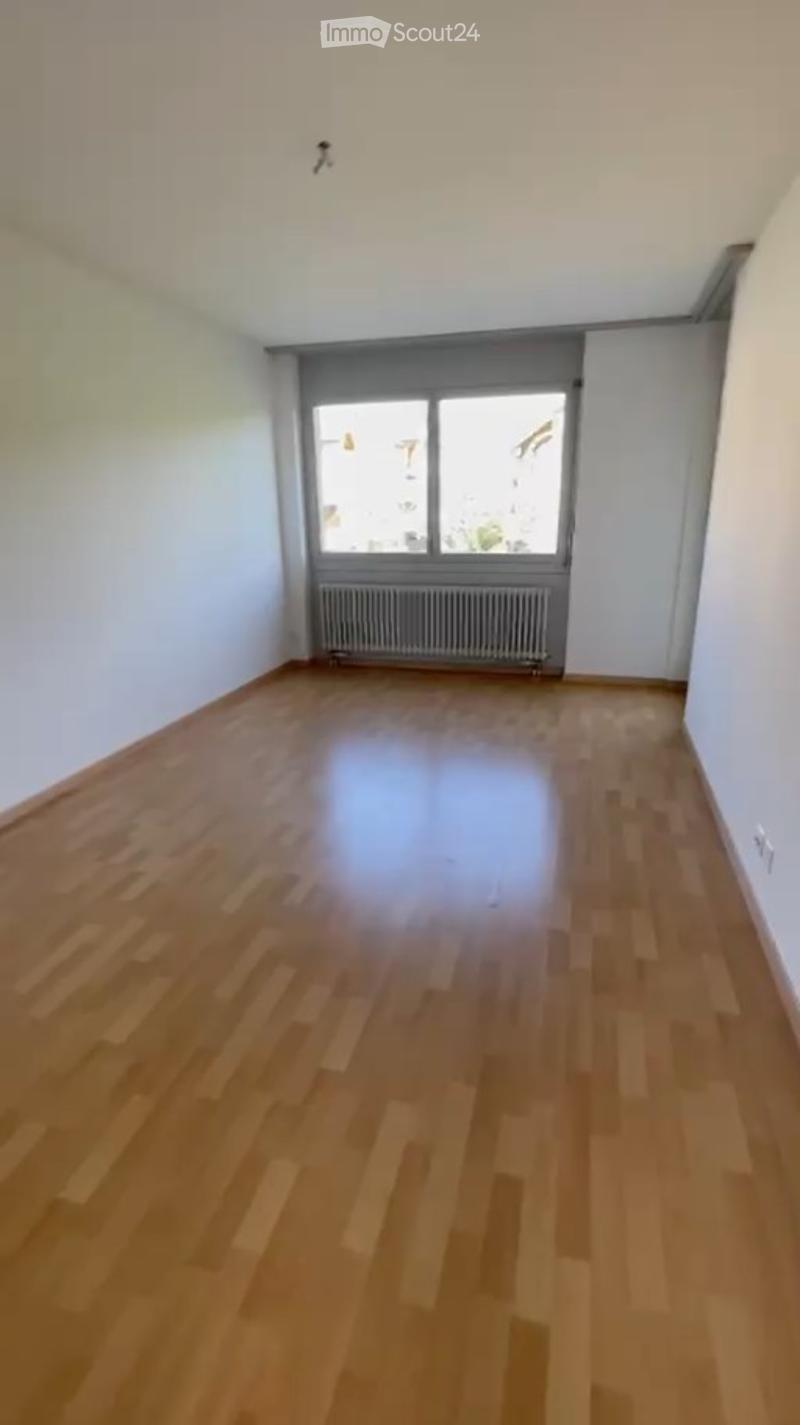 Unfurnished Room. Empty room with wooden flooring, white walls, and a large window with a radiator below it.