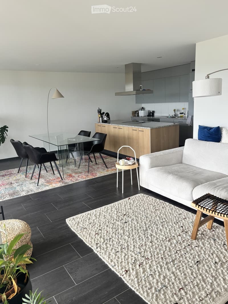 Modern open-plan living and dining area with a sofa, coffee table, dining table with chairs, kitchen island, and floor lamp.