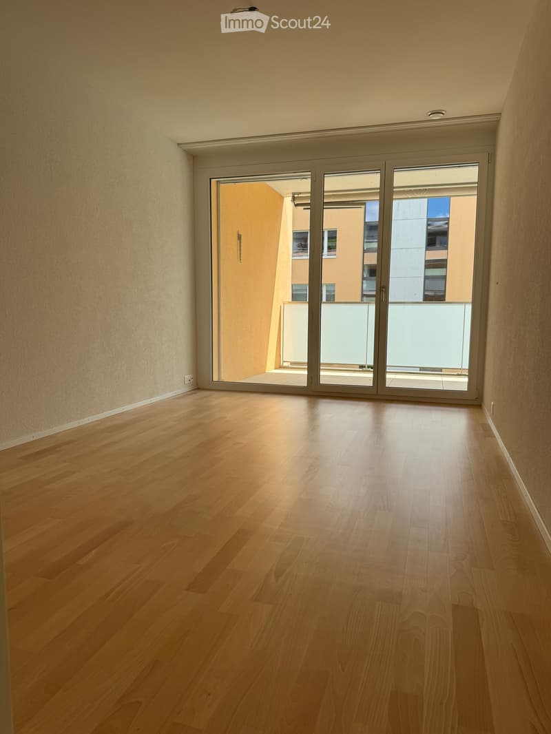 Empty room with wooden flooring and large sliding glass doors leading to a balcony area.