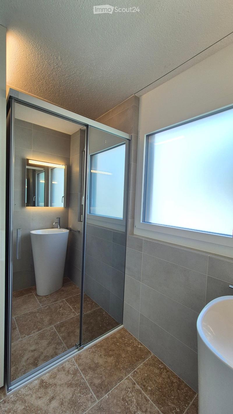 Modern bathroom with shower, pedestal sink, round bathtub, tiles on the floor, mirror with lighting