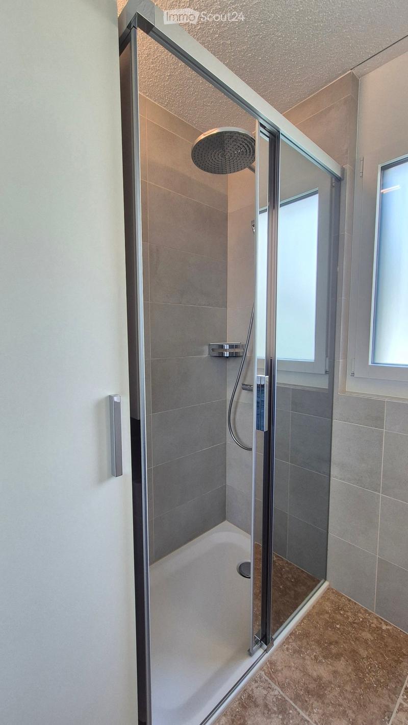 shower area, glass shower enclosure, showerhead, tiled floor, mirror, window