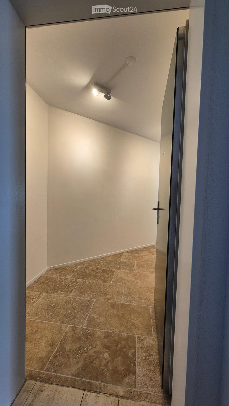 Empty hallway with white walls, tiled floor, and white ceiling with ceiling lamp.