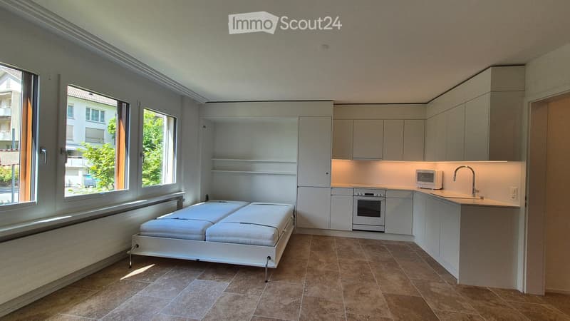 small room with bed, microwave, oven, sink, open shelves, windows