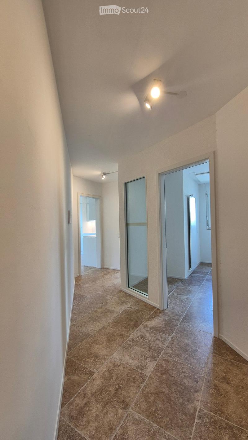 tiled floor, white walls, two ceiling lights, glass doors to other rooms