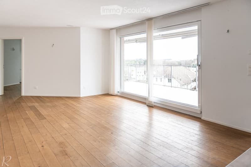 Empty room with wooden flooring, white walls, and large sliding glass doors leading to a balcony.