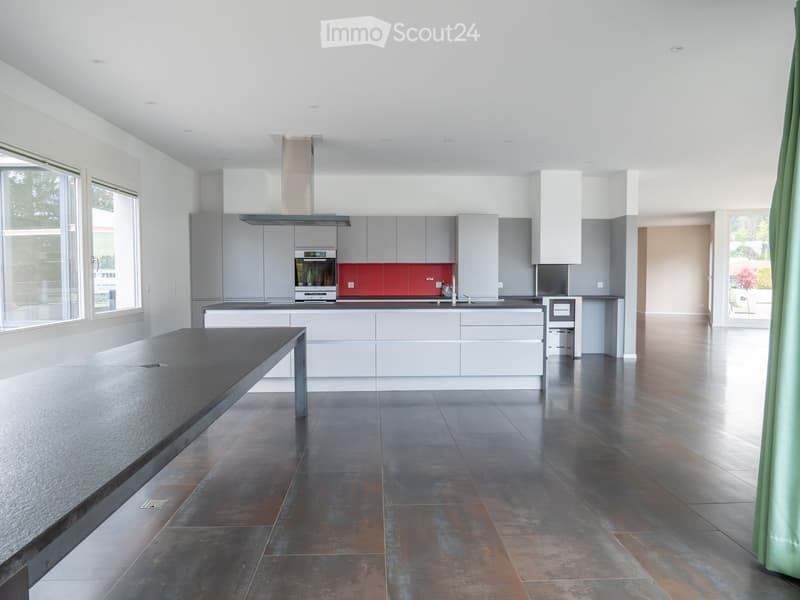 Modern kitchen with grey cabinets, stainless steel appliances, a central island, and a dark tiled floor.