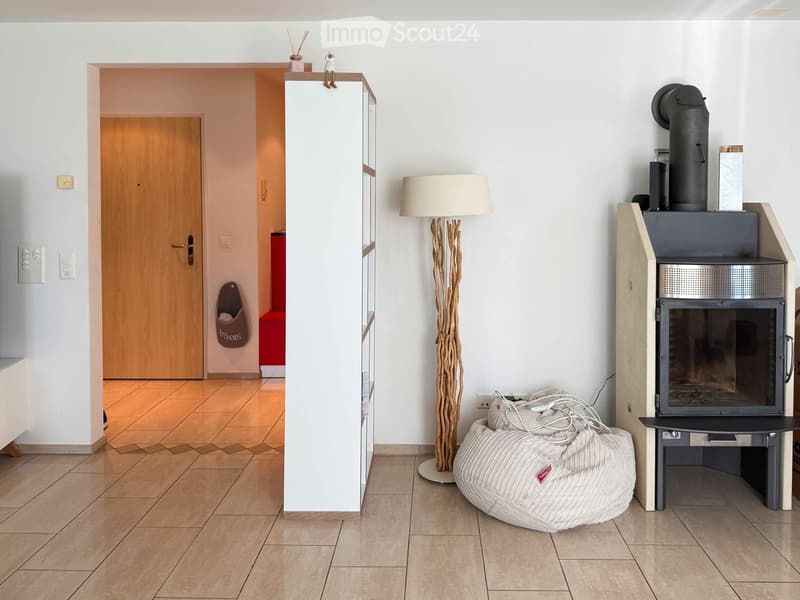 Modern living room with a fireplace, floor lamp, bean bag chair, and a shelf with decorative items.