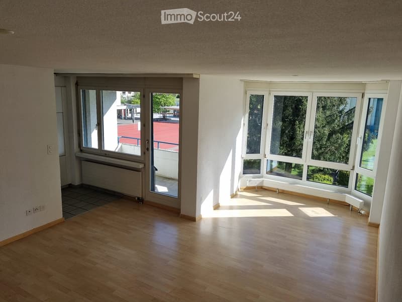 Empty room with wooden flooring, large windows, and radiators. No furniture or equipment present.