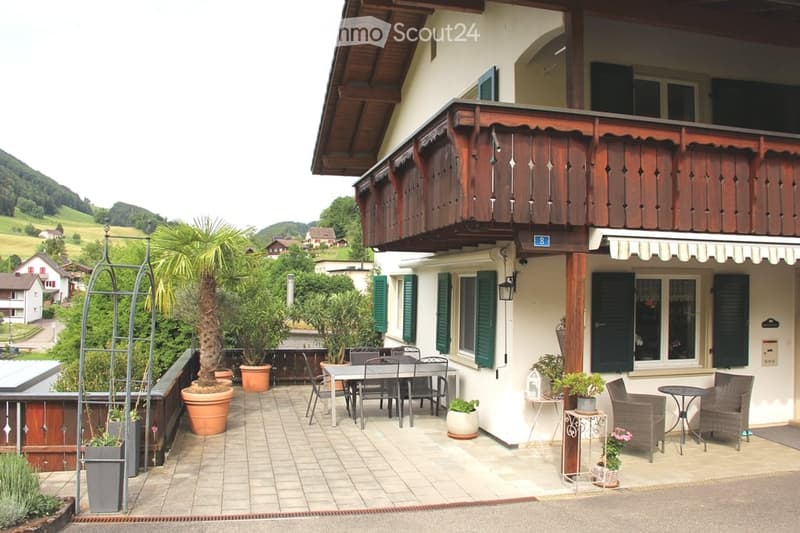 Balcony area with outdoor furniture, potted plants, and scenic countryside view.
