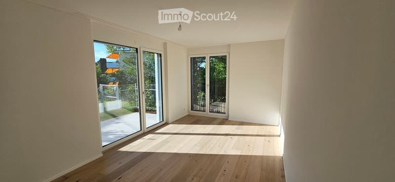 Empty room with wooden flooring, white walls, and large sliding glass doors leading to an outdoor area.