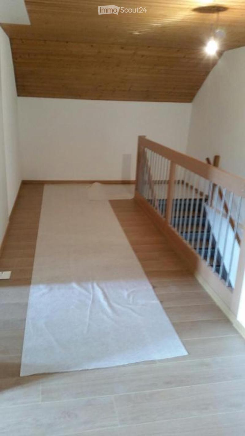 Empty room with wooden flooring and a wooden staircase railing, no furniture or equipment present.