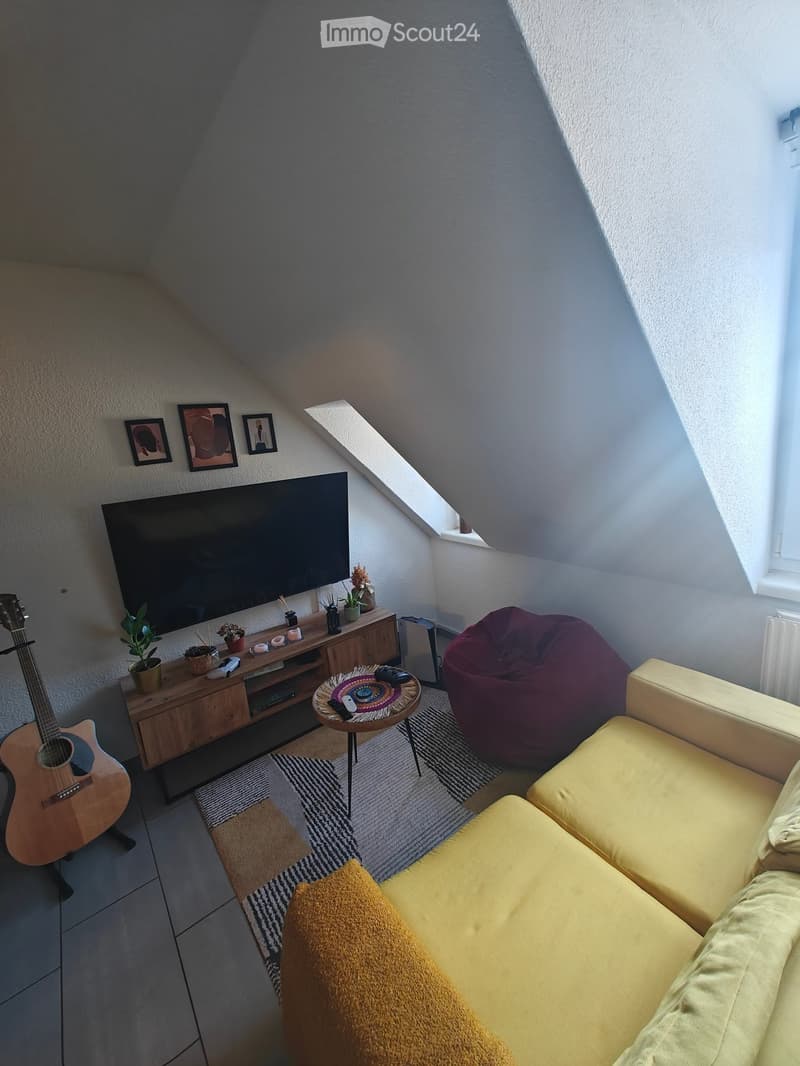 Living room with a yellow sofa, coffee table, beanie chair, guitar, television, wooden cabinet, and decorative items.