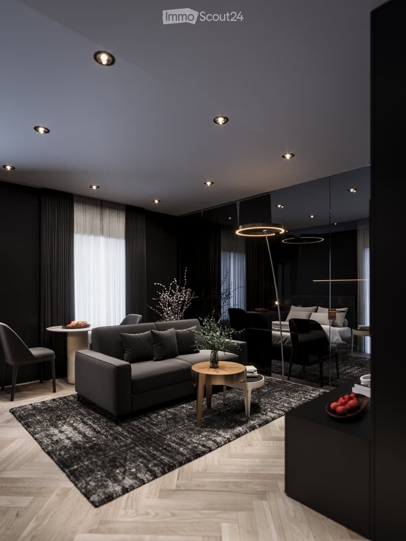 Modern living room with black furniture and beige wooden floor, large grey sofa, round wooden coffee table, potted plants, floor lamp, carpet, and round mirror.