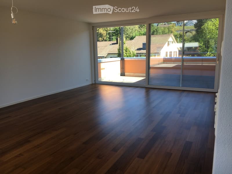 Empty room with wooden flooring and large sliding glass doors leading to a balcony or terrace area.