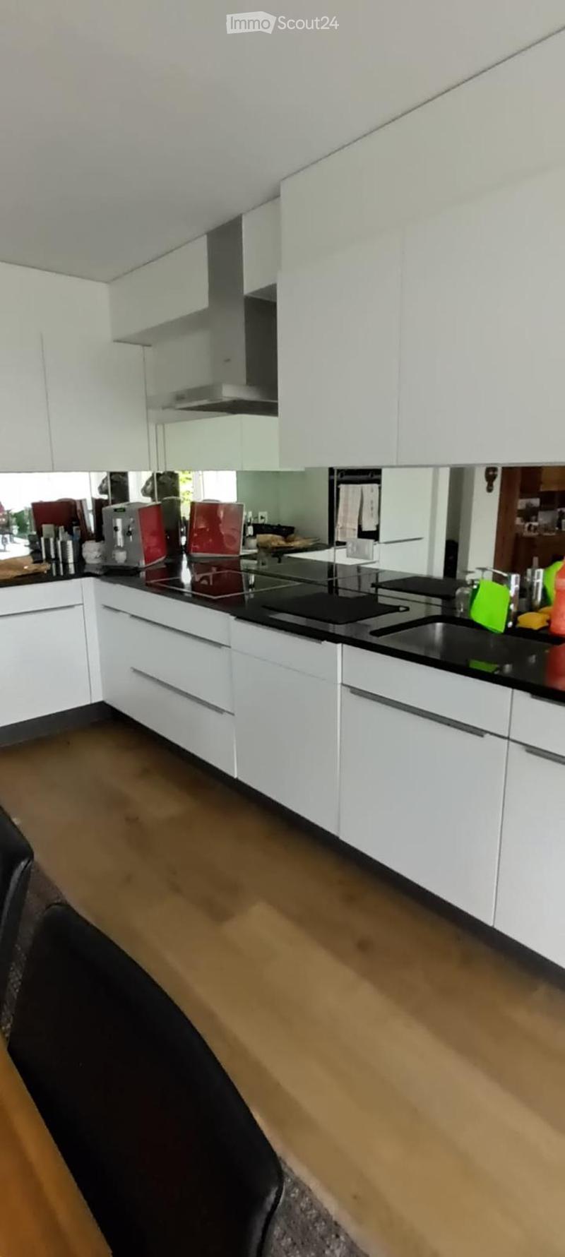 Modern kitchen with white cabinets, black countertop, and stainless steel appliances. Features include a sink, coffee maker, oven, and stove.