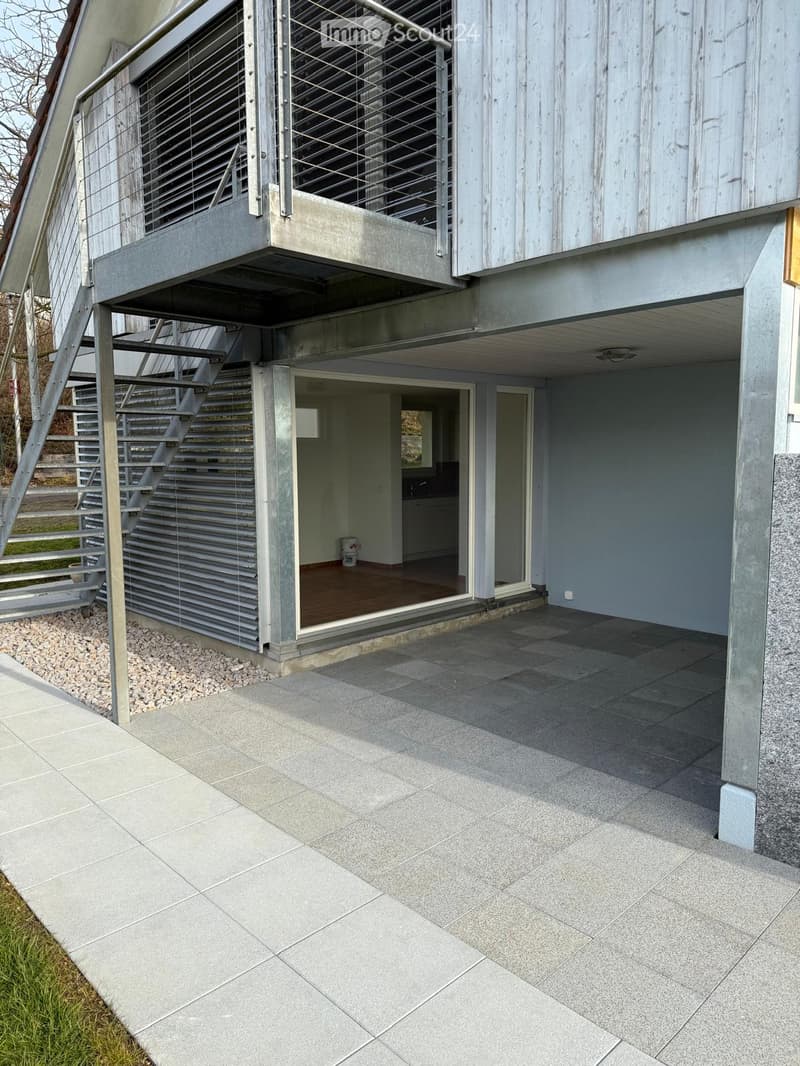 modern building, gray exterior, balcony, stairs, large glass door, paved exterior
