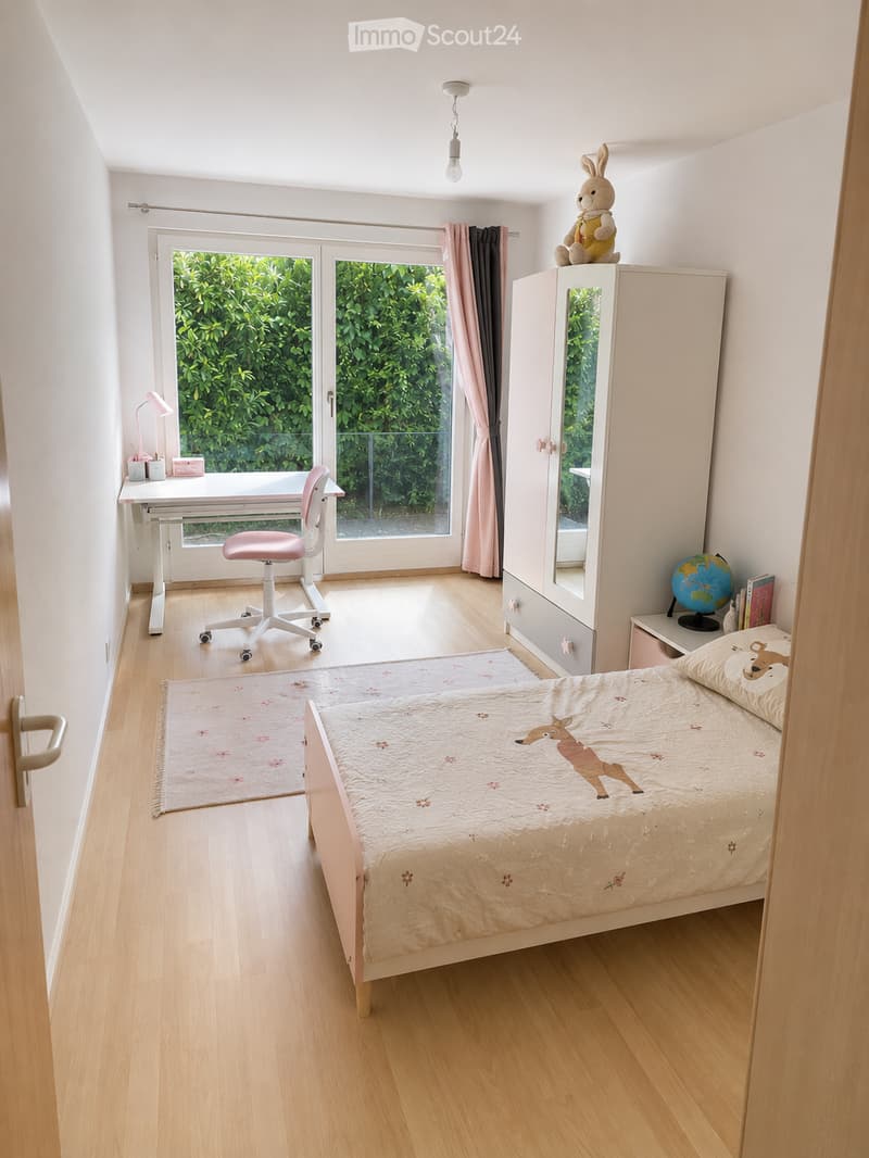 Bright, modern bedroom with a single bed, desk, chair, wardrobe, and a view of greenery through large windows.