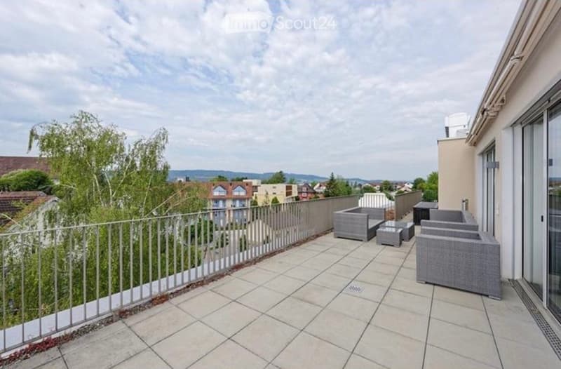 Balcony with tiled floor, metal railing, and outdoor furniture including a sofa, table, and chairs.
