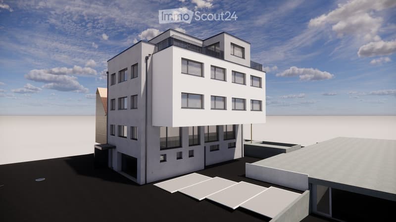 A modern building with multiple floors and windows, featuring a flat roof and a small balcony on the top floor.