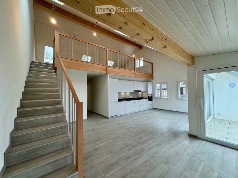 open floor plan, wooden stairs, wooden balcony, kitchen, white cabinets, tiled floor