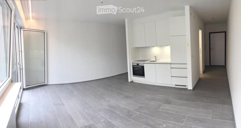 Modern kitchen with white cabinets, stainless steel oven, sink, and faucet. Grey tiled floor and large windows.
