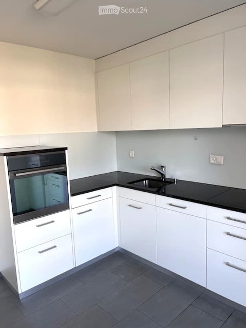 Modern kitchen with white cabinets, black countertops, and a built-in oven. Features a sleek sink with a modern faucet.