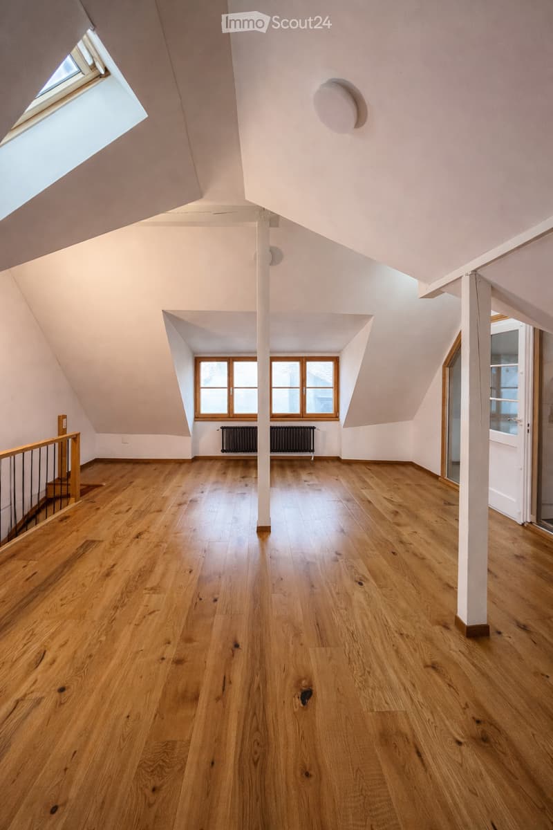 empty attic room, wooden floor, skylight, windows, wooden support column, open door