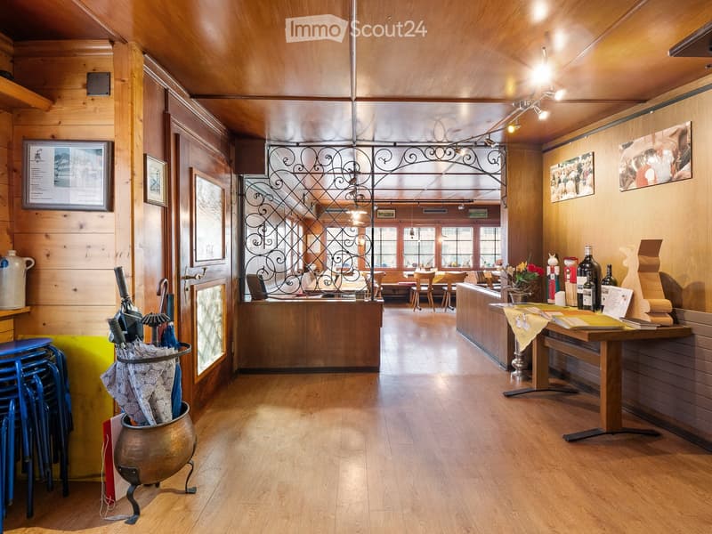 A well-lit, wooden-paneled reception area with a reception desk, chairs, a table with books and wine bottles, and a decorative umbrella stand.