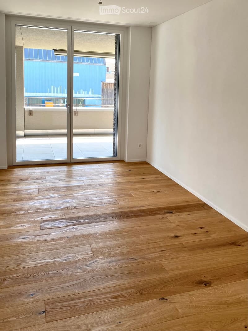 Empty room with wooden flooring and large sliding glass doors leading to a balcony.