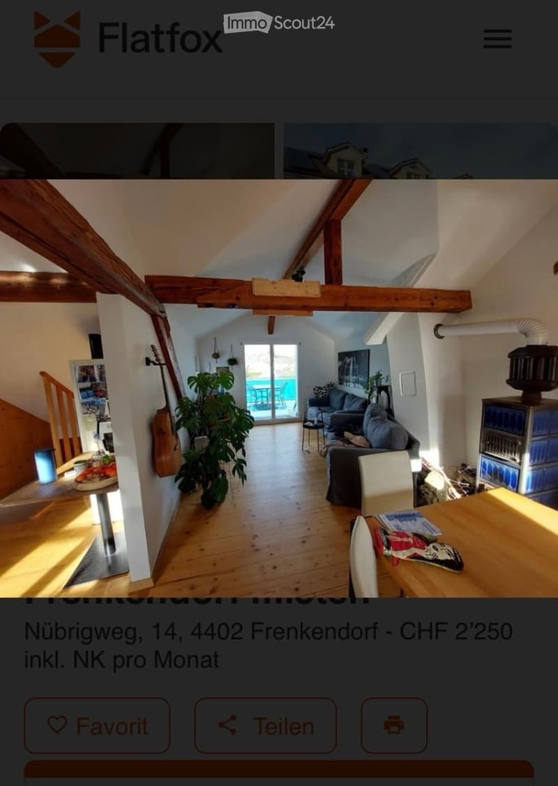 Bright, open-plan living and dining area with wooden floors, exposed wooden beams, large windows leading to a balcony, sofa, dining table, chairs, and a guitar leaning against the wall.