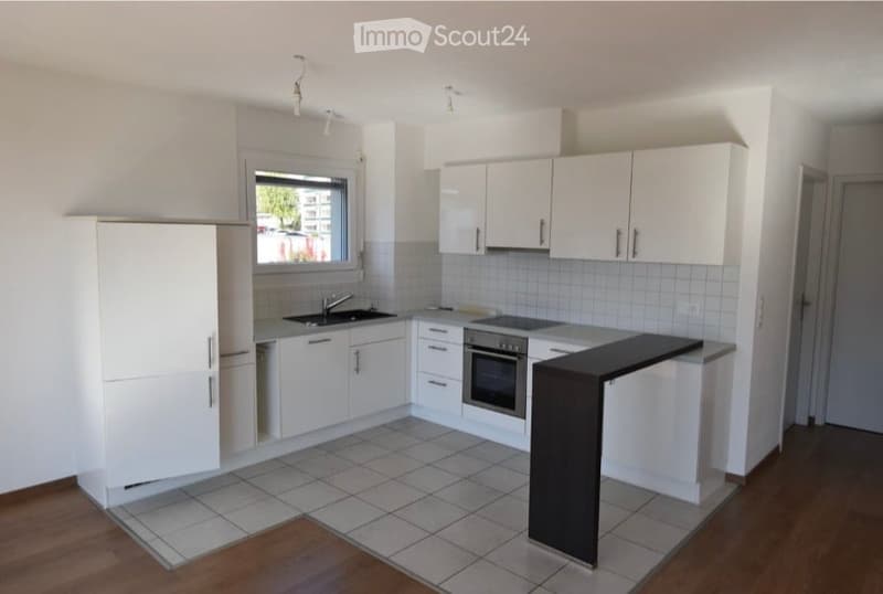 Modern kitchen with white cabinets, a sink, an oven, and a countertop. The space features tiled flooring and a window providing natural light.