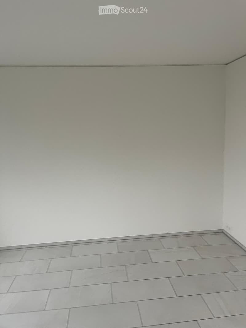 Empty room with light grey tiled floor and white walls, no furniture or equipment.