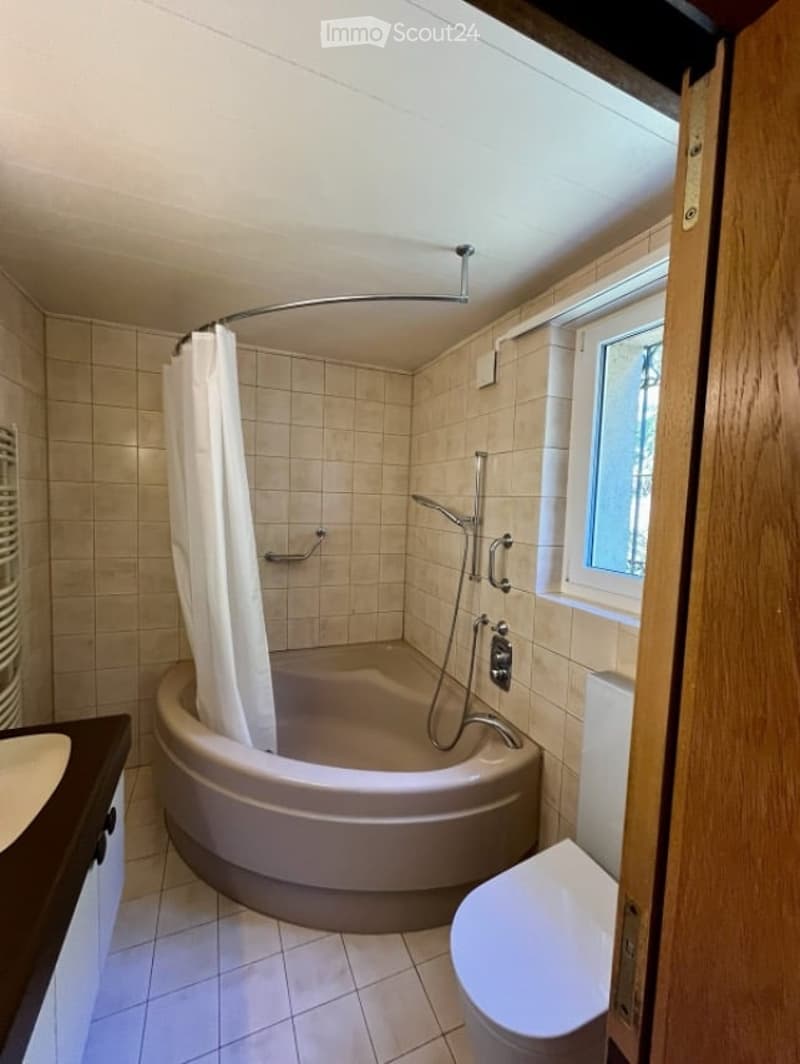 Bathroom with a bathtub, shower curtain, toilet, sink, faucet, and shower head.