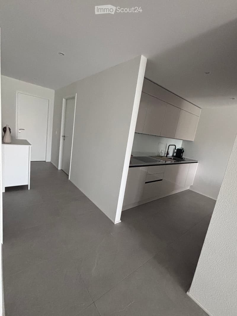 Empty kitchen with grey tiled floor, white cabinets, and a sink area. No furniture or appliances visible.