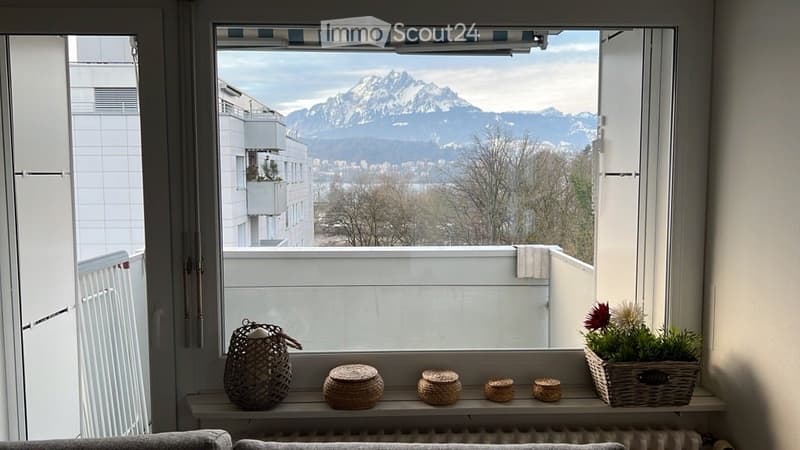 Balcony with a scenic mountain view, decorated with a basket and flower pot on the windowsill.