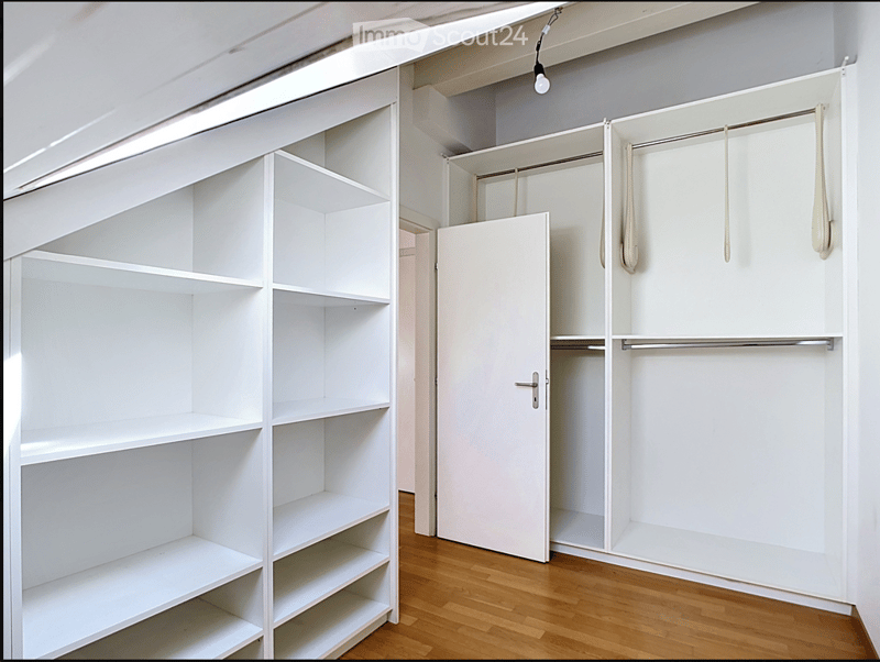 Empty room with white built-in shelving units and a wooden floor. No furniture or personal items present.