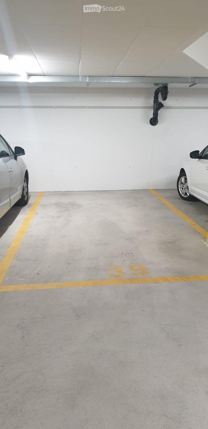 Underground parking space with two cars parked on either side, marked with yellow lines and numbered '39'.