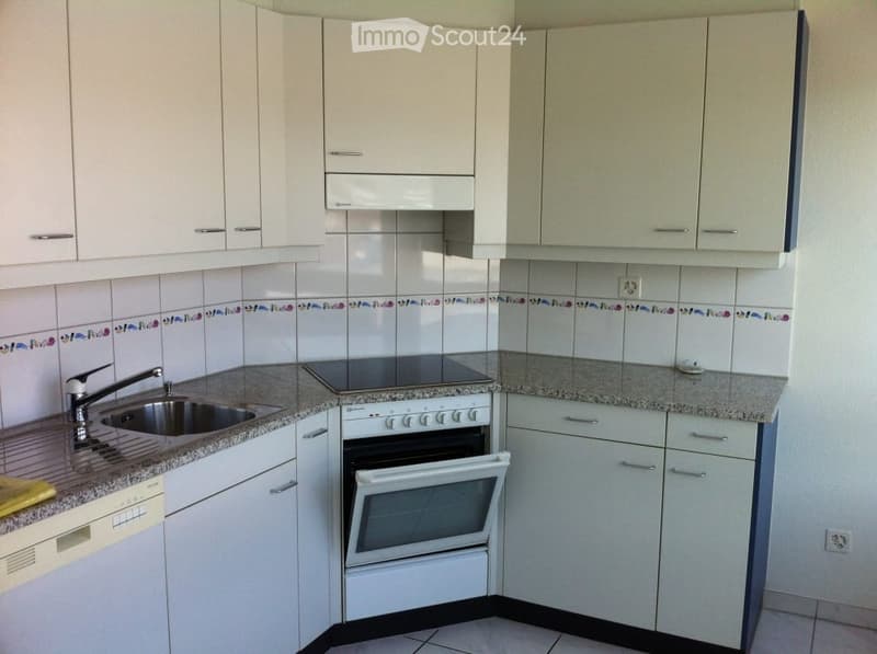 Modern kitchen with white cabinets, granite countertops, a sink, and an oven. The backsplash features a decorative tile border.