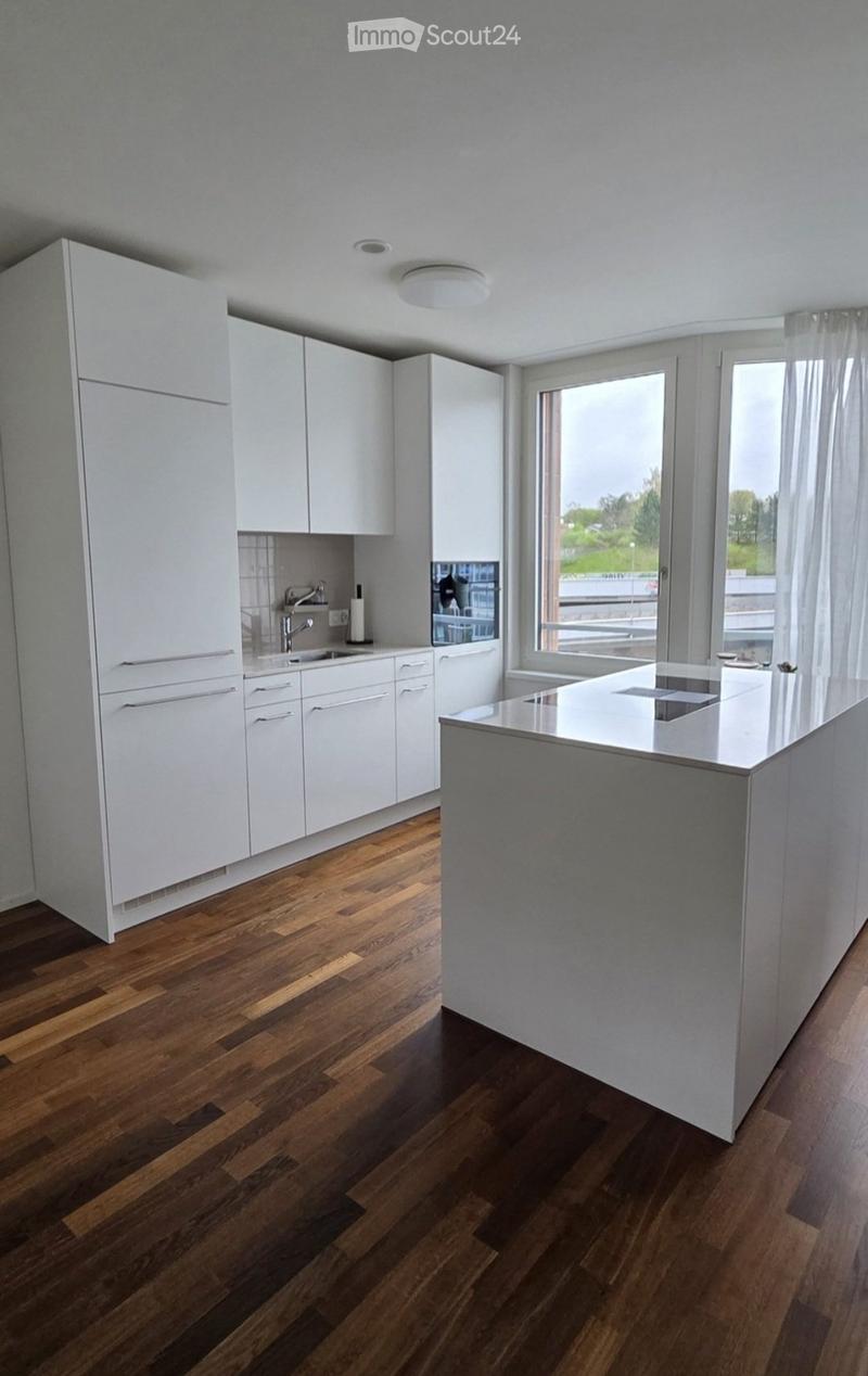 Modern kitchen with white cabinets, wooden flooring, and a central island with a countertop.